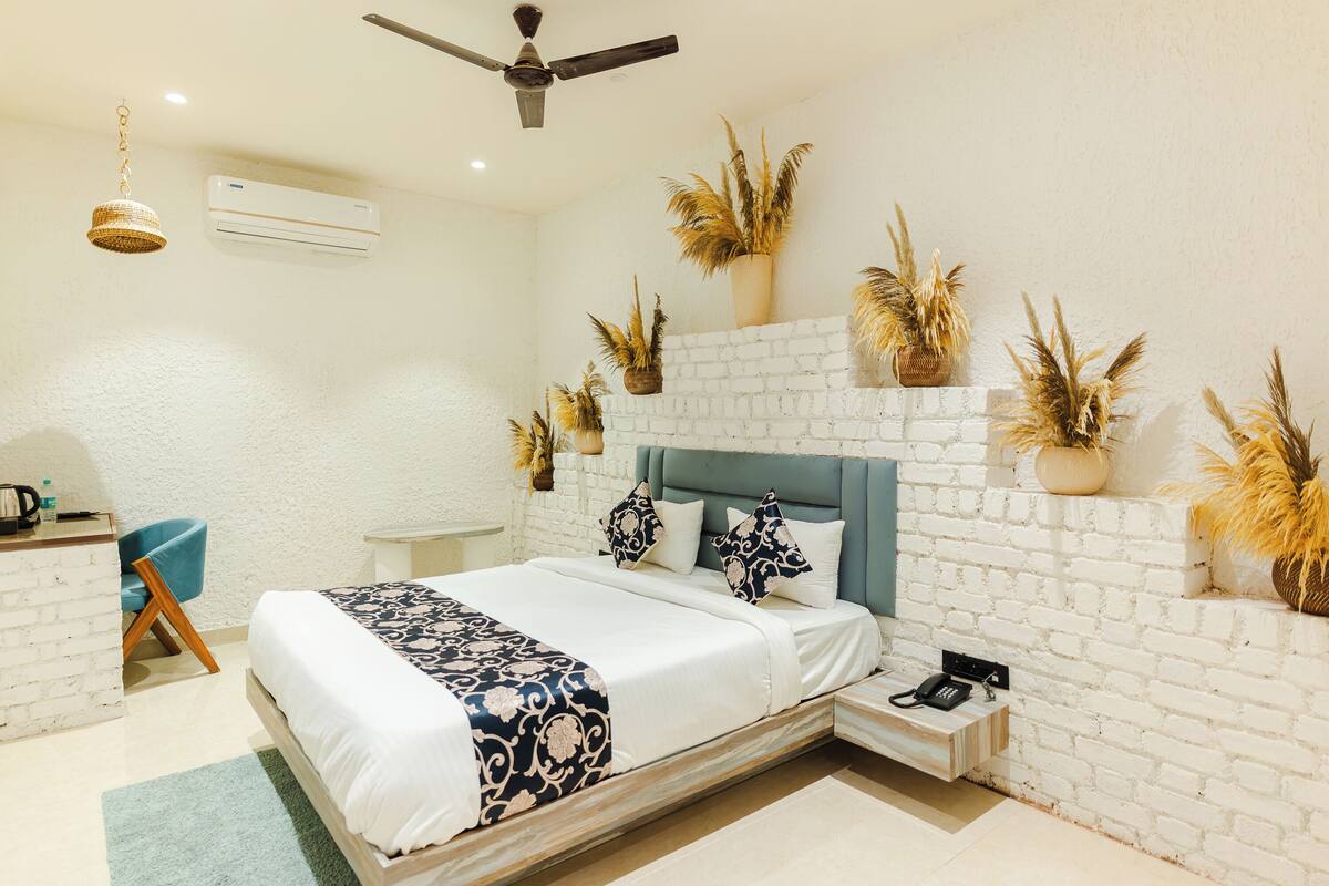 Een slaapkamer met een bed, een bureau, een stoel en een aan de muur bevestigd toestel.