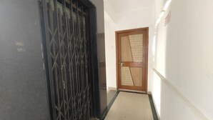 A hallway with a black metal gate and a wooden door with a geometric design. - Sairam Executive (Pune)