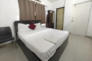 Quarto de hotel com cama, guarda-roupa, escrivaninha e cadeira.