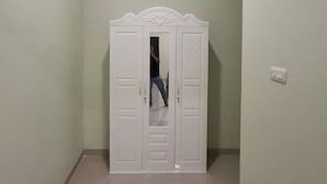 Un armadio bianco con ante a specchio e decorazioni sulla sommità.