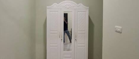 Un armario blanco con puerta espejada y detalle decorativo en la parte superior.