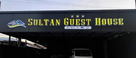 A sign for the Sultan Guest House with a logo and name.