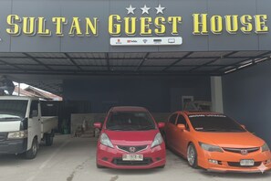 A building with a sign reading "SULTAN GUEST HOUSE" and three parked cars in front. - Sultan Guest House (Palu)