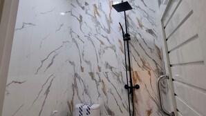 Un bagno con il water, una doccia e una parete in marmo.