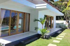 A modern house with large sliding glass doors, a pool, and a well-maintained garden. - Padi-Padi Pool Villas (Kubutambahan)