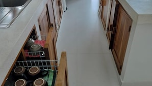 A narrow kitchen with wooden cabinets and a stainless steel sink. - Padi-Padi Pool Villas (Kubutambahan)