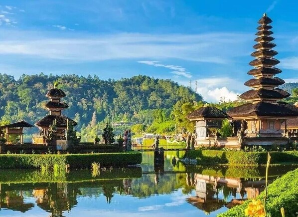 Un complejo de templos sereno con pagodas escalonadas y un estanque tranquilo que refleja las estructuras.