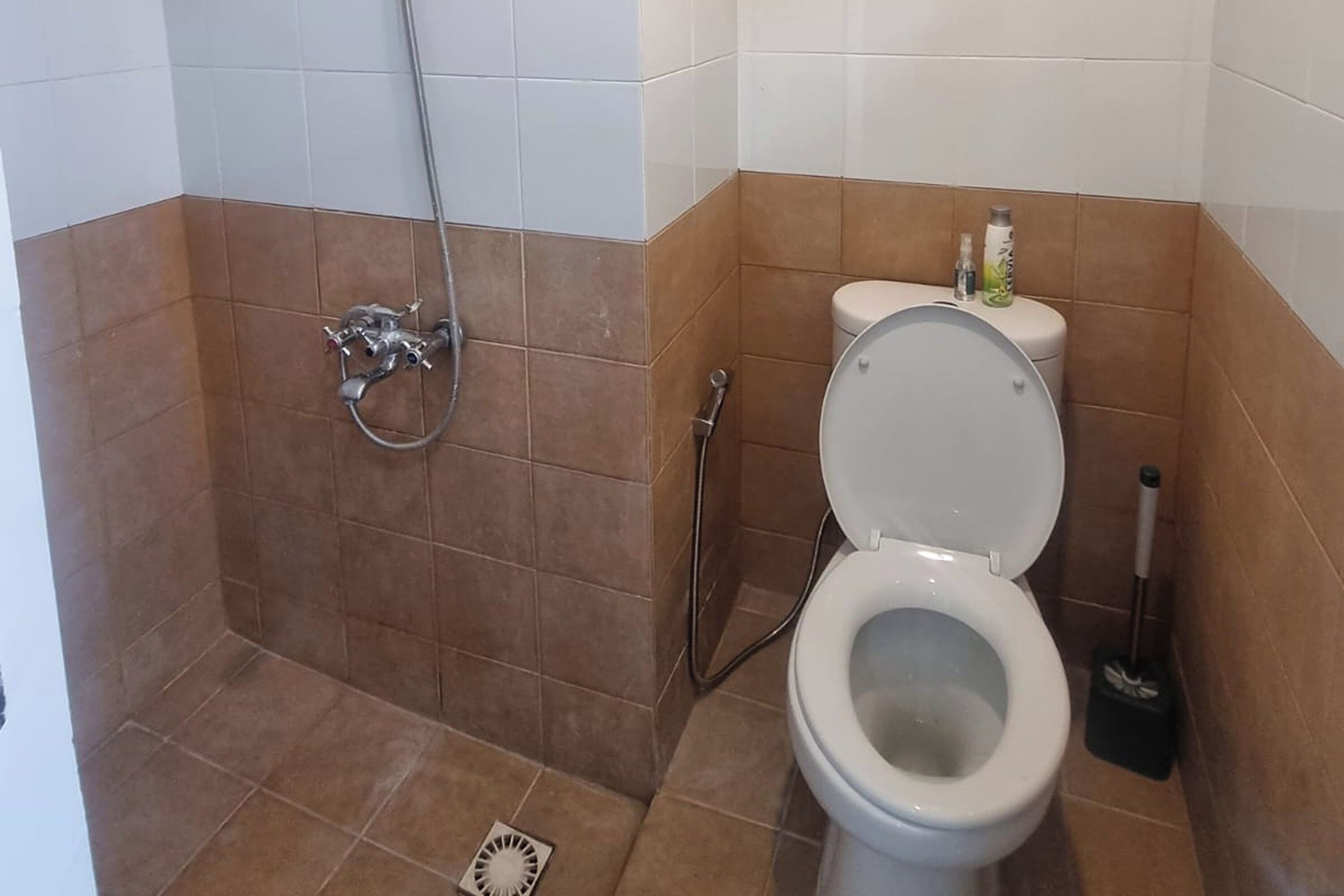 A bathroom with a toilet, shower, and a bidet.