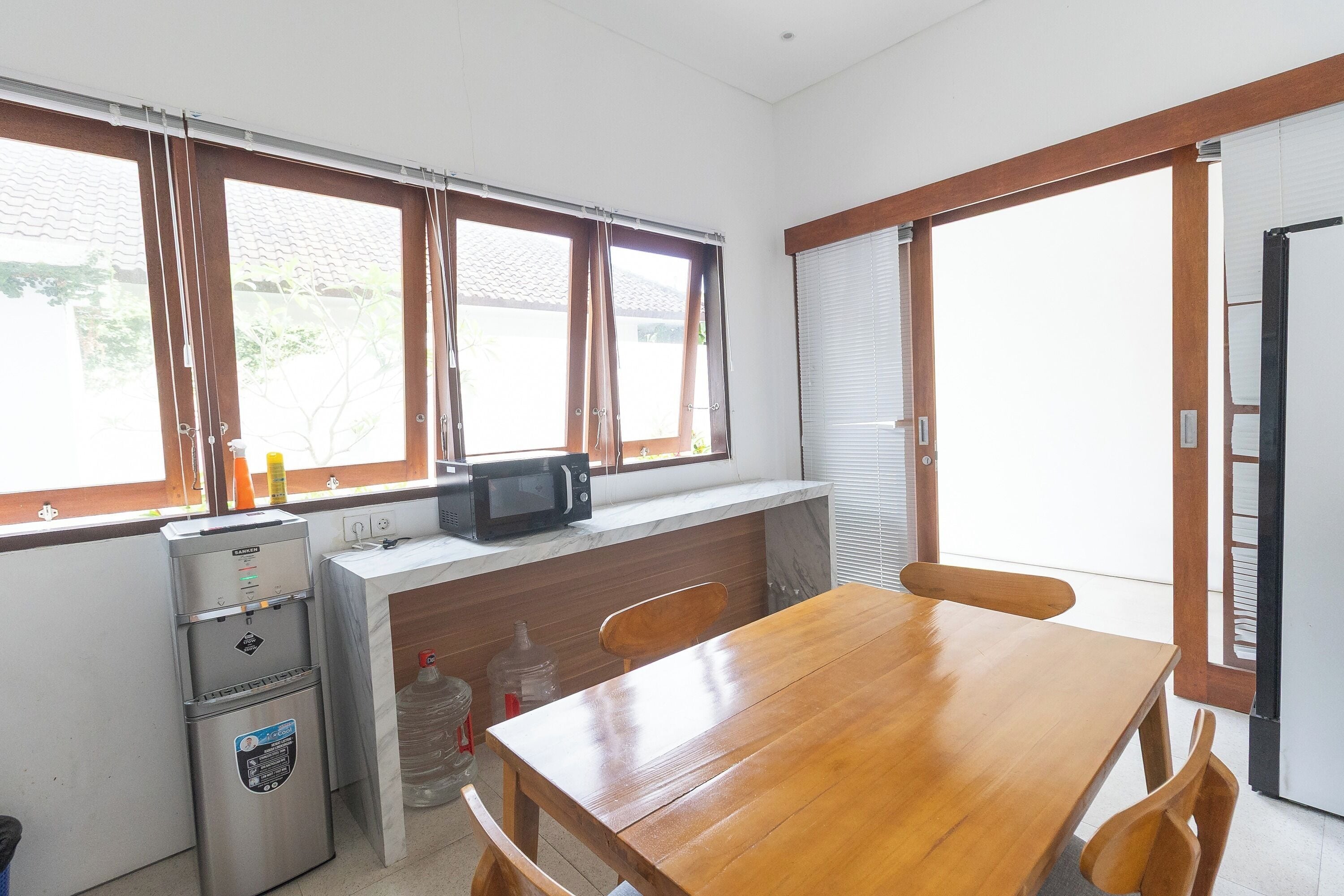 Una cocina con una mesa de madera, un refrigerador, un microondas y un dispensador de agua.