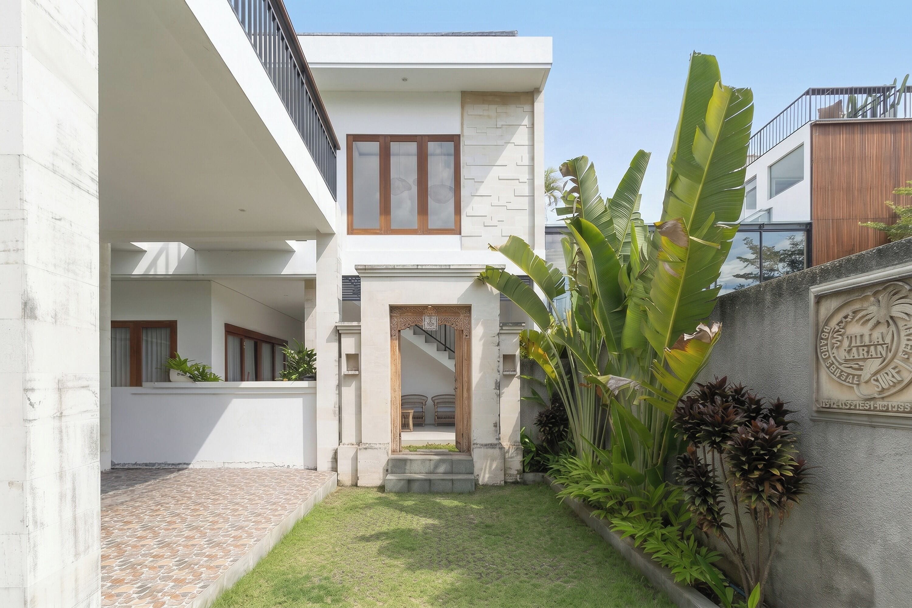 A modern two-story building with a central courtyard, a staircase leading to the upper floor, and a sign indicating the name 'Villa Karani.'