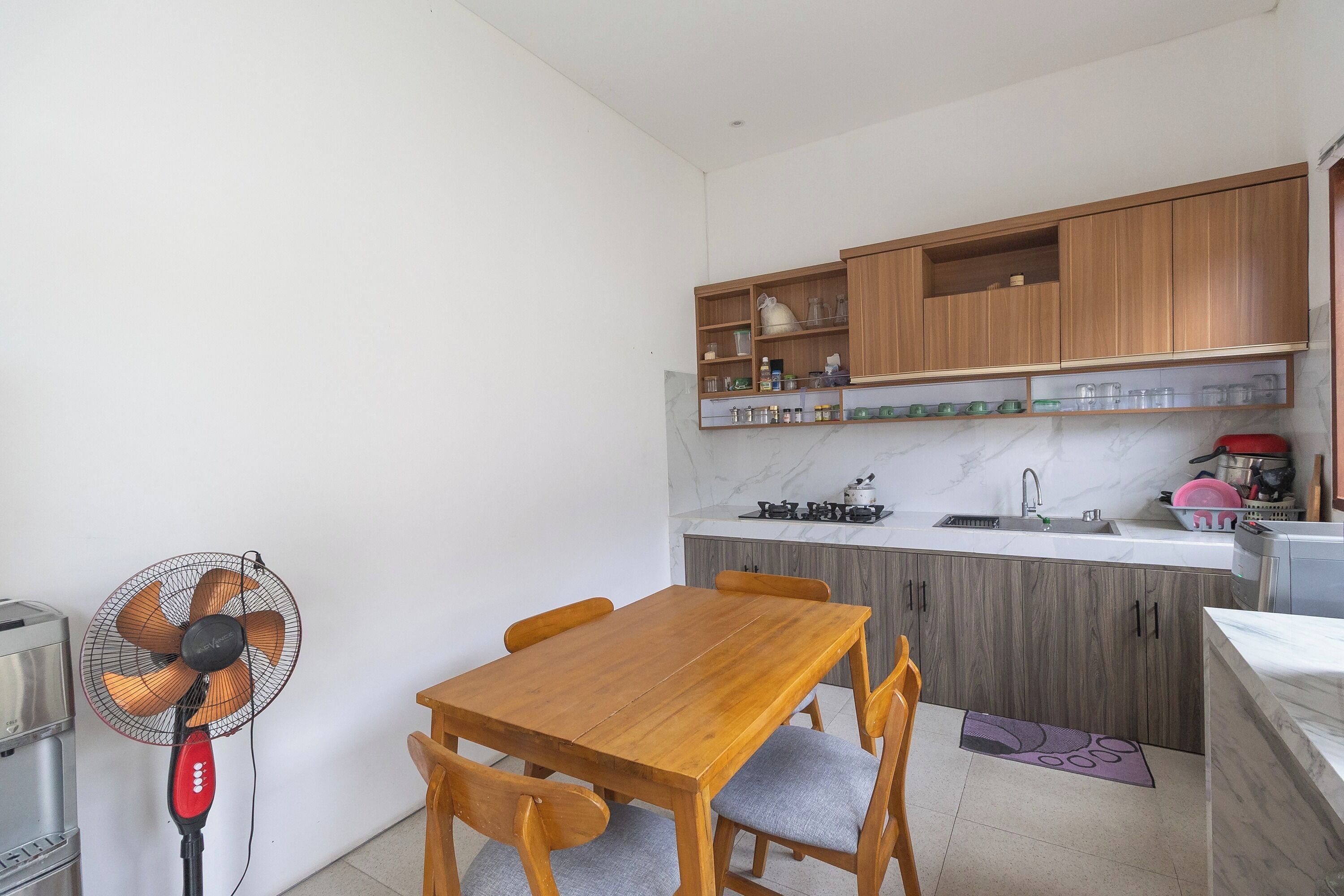 Une cuisine avec des meubles en bois, un plan de travail en marbre et une table à manger avec des chaises.