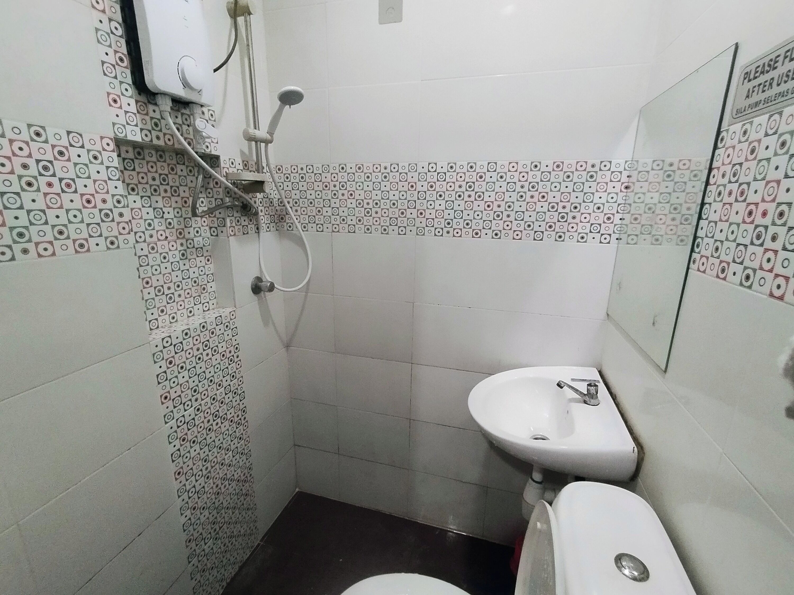 A small, tiled bathroom with a toilet, sink, and shower.