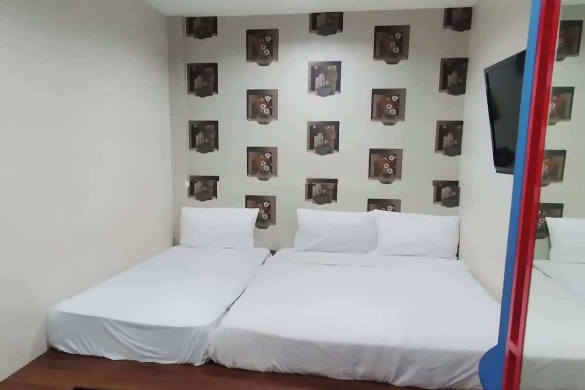 A room with two single beds, a wooden bench, and a wall decorated with framed pictures.