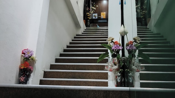 A staircase with handrails, leading to a landing. There are flower arrangements on the walls beside the stairs. - Cahaya Hanson (Bilikxpert) (Kuala Lumpur)