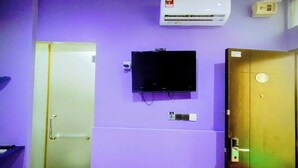 A room with purple walls, a mounted television, a door with a lock, and an air conditioning unit. - Cahaya Hanson (Bilikxpert) (Kuala Lumpur)