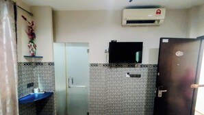 A hotel room with a bed, a small desk, a mirror, a wardrobe, and an air conditioning unit. - Cahaya Hanson (Bilikxpert) (Kuala Lumpur)