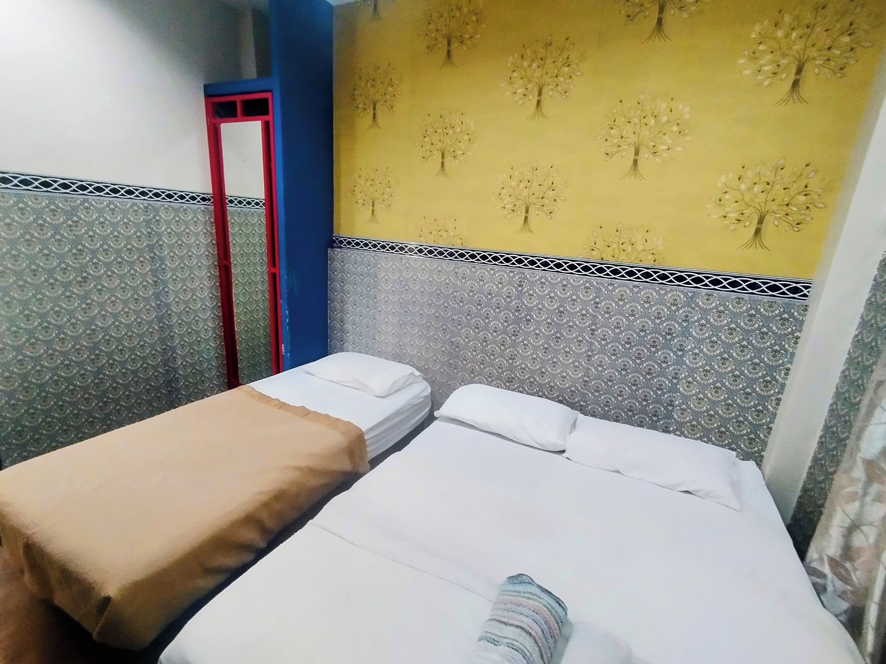 Ein Zimmer mit zwei Betten, eines mit einer braunen Decke und das andere mit einer gestreiften Decke.