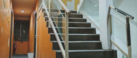 A staircase with glass railings and a handrail, leading to an upper floor.