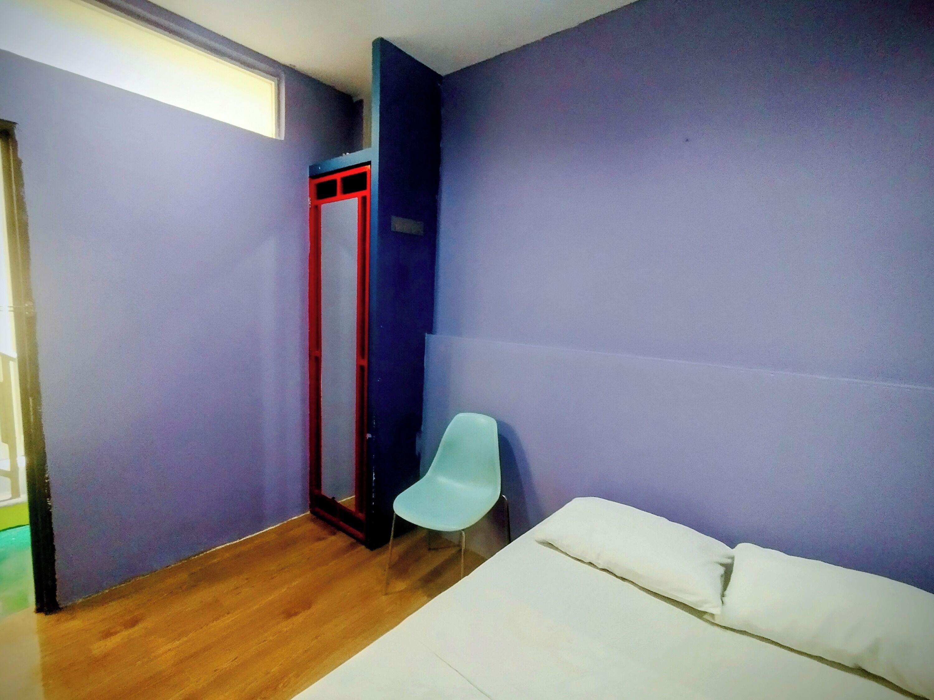 Ein Zimmer mit einem Bett, einem Stuhl und einer Tür.