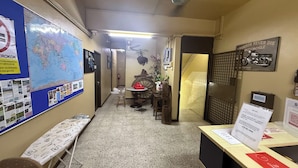 A reception area with a desk, chairs, a map, and a motorcycle sign. - Aikka Hotel (Butterworth)