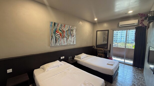 A hotel room with two beds, a desk, a chair, a large abstract painting, and a view of the outside. - Aikka Hotel (Butterworth)
