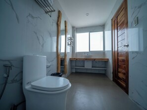 A bathroom with a toilet, a wooden vanity with a mirror, and a window providing natural light. - Turtle Beach Resort (San Juan)