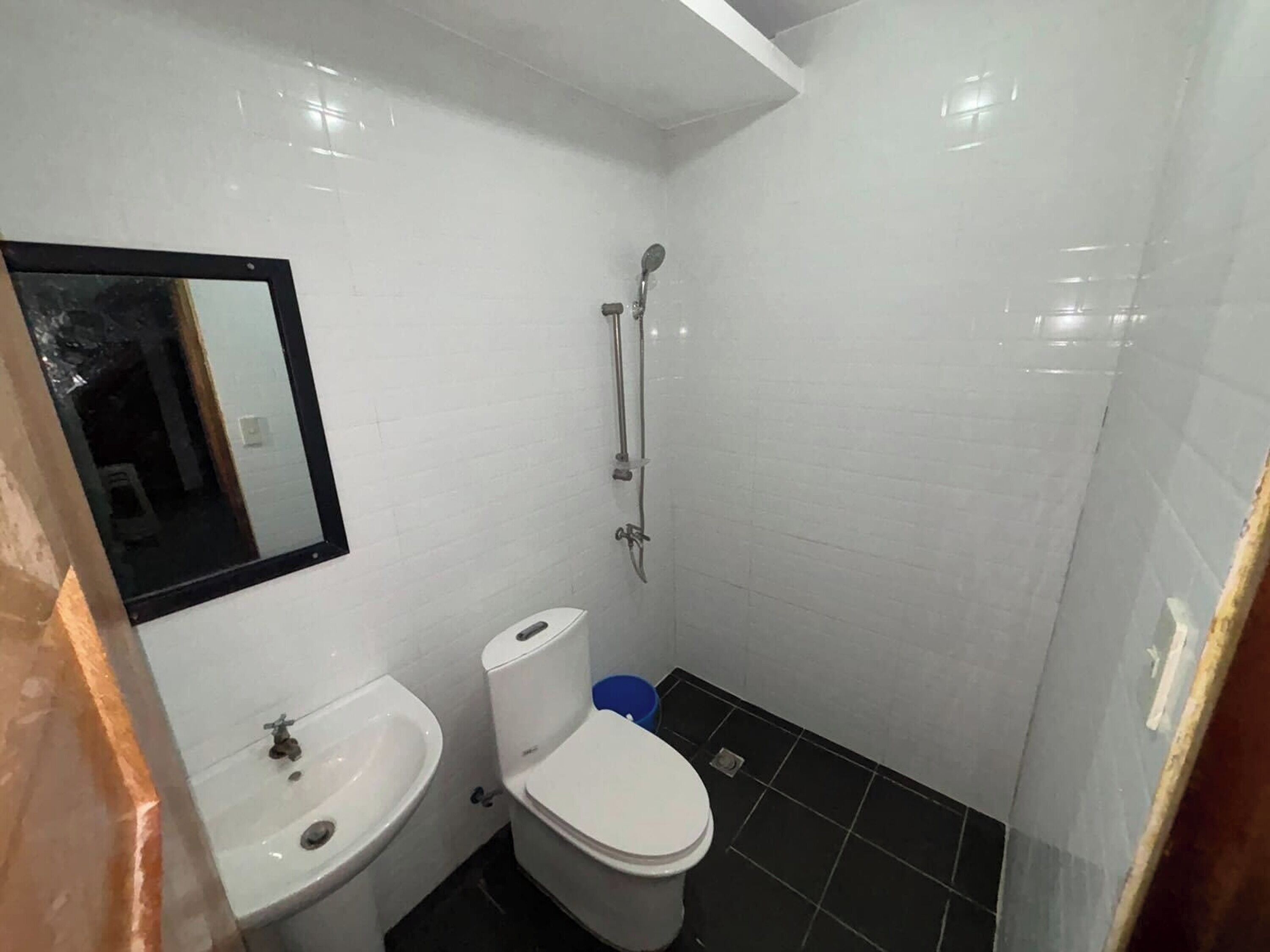 Un baño pequeño y funcional con lavamanos, inodoro y ducha blancos.