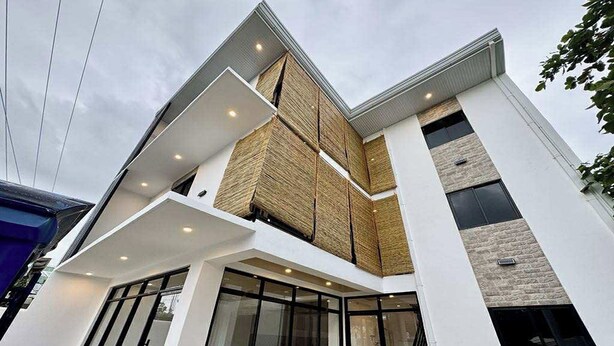 A modern building with a prominent corner entrance, large glass doors, and a mix of brick and wooden facade elements. - Eva'S Guest House (General Luna)