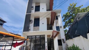 A multi-story building with balconies, large windows, and a fire extinguisher on the exterior wall. - Eva'S Guest House (General Luna)