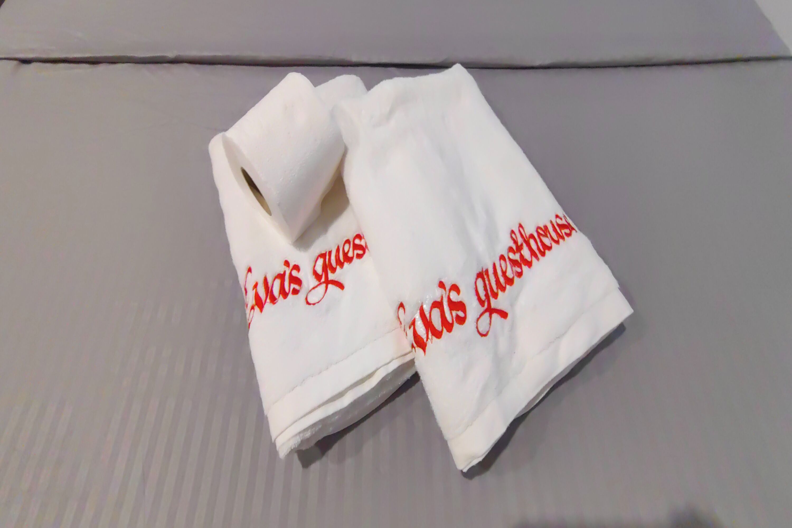 Una toalla blanca doblada con texto rojo sobre una cama.