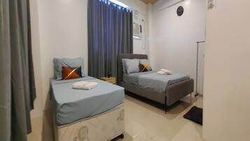 Una habitación de hotel con dos camas, una mesita de noche y un reloj.
