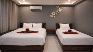 Habitación de hotel con dos camas, aire acondicionado de pared y un arreglo floral decorativo.