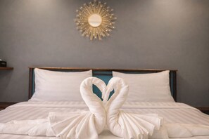 Quarto de hotel com cama, almofadas e um espelho decorativo fixado na parede.