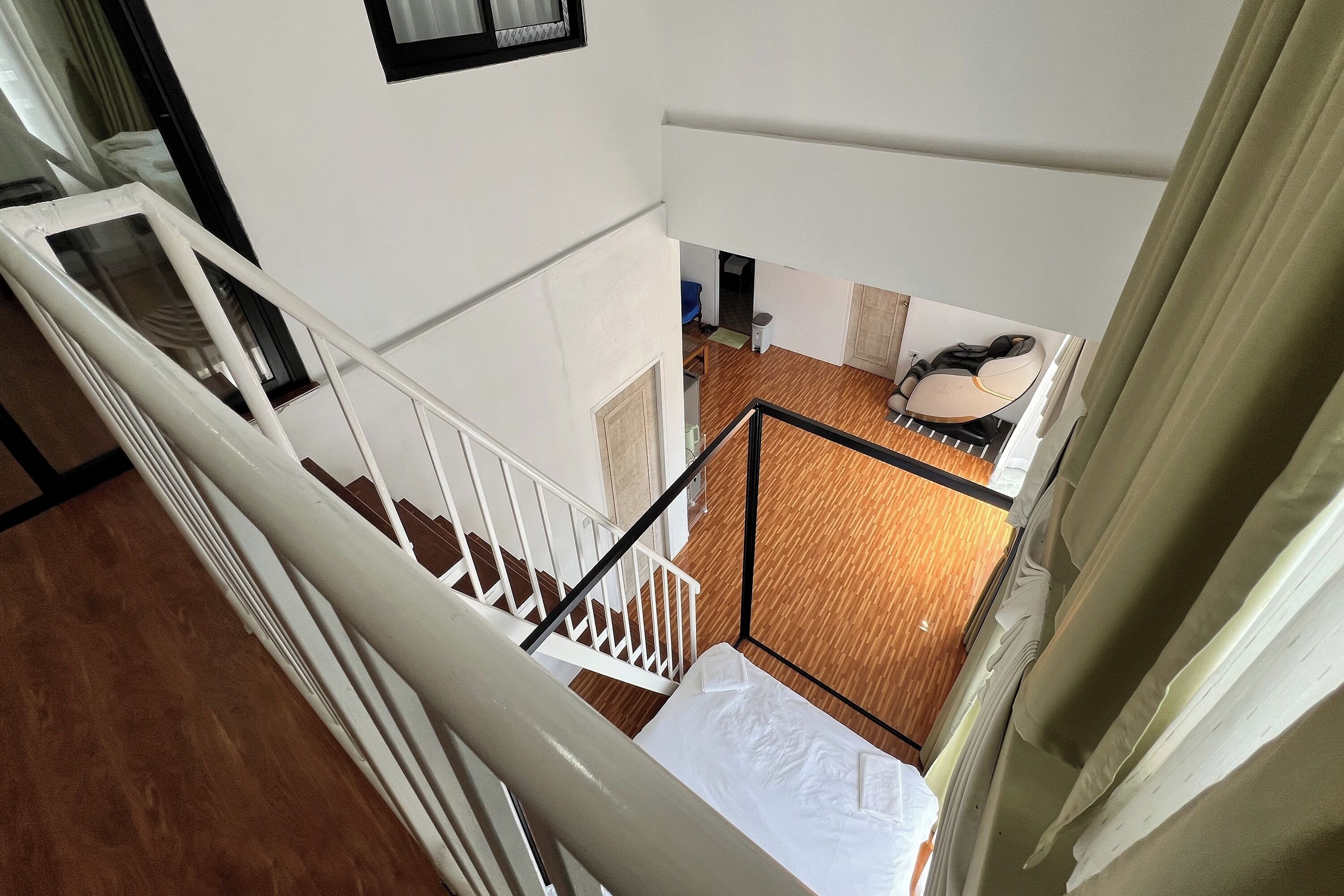 Un interior de varios niveles con una escalera, piso de madera y vistas a una habitación con una silla y una mesa.