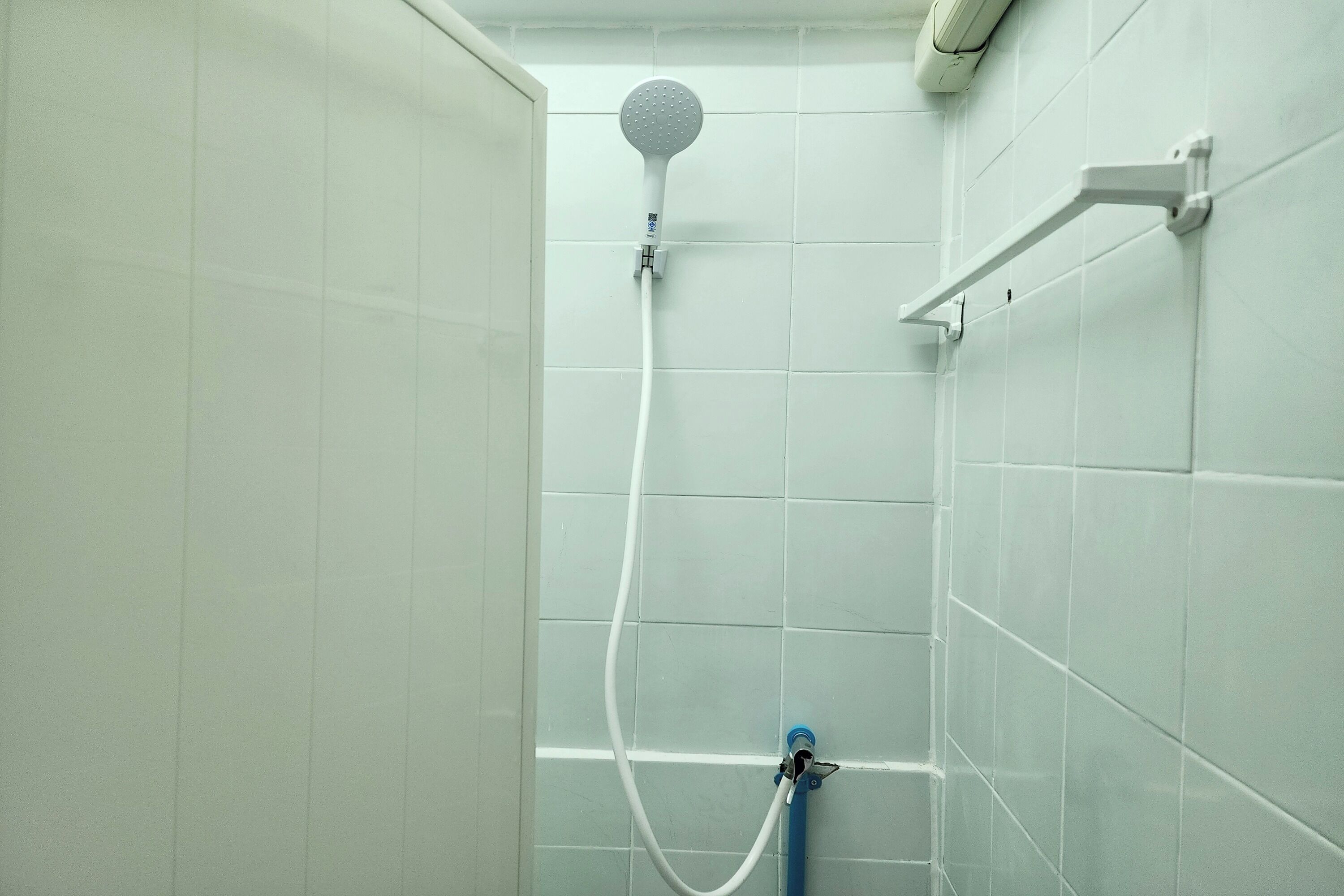 Ducha con cabezal de ducha de mano y palanca de control en la pared.