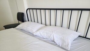 Ein Bett mit weißer Bettwäsche und einem schwarzen Metall-Kopfteil.