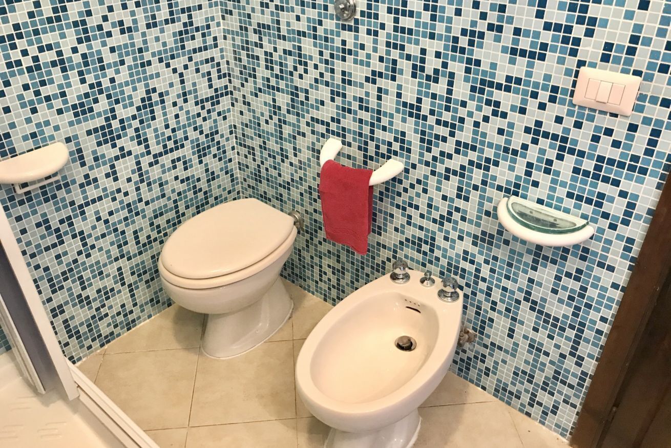 A bathroom with a toilet, bidet, and tiled walls.