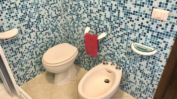 A bathroom with a toilet, bidet, and tiled walls.