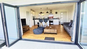 A modern interior with a sofa, a coffee table, and a bean bag chair in a living area. - Holywell Luxury Lodge with Hot Tub | Relax, Unwind & Enjoy Cornish Sunsets (Goonhavern)
