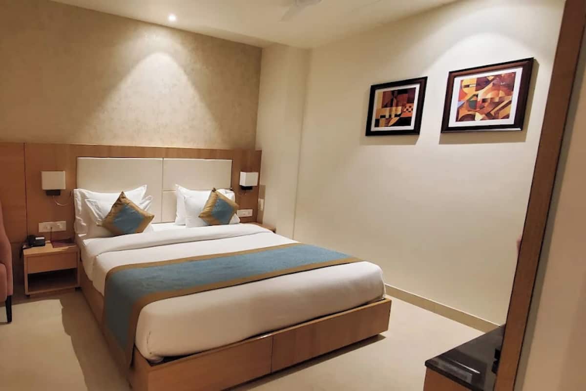 Ein Hotelzimmer mit Bett, Nachttisch, Stuhl und einem Kunstwerk an der Wand.