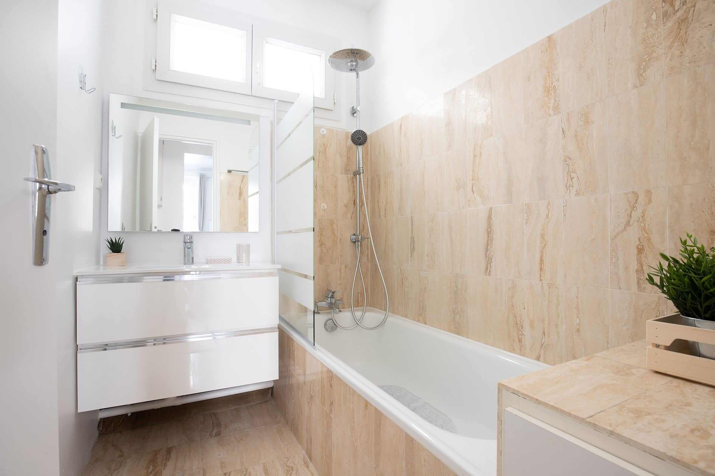 A modern bathroom with a bathtub, a shower, a large mirror, and a vanity with a sink.