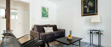 Una sala de estar moderna con un sofá, sillas, una mesa de centro y un cuadro en la pared.