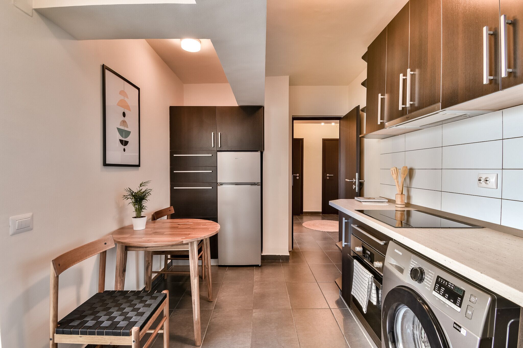 Una cocina compacta con comedor, lavadora y refrigerador.