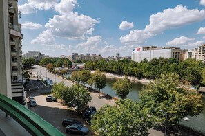 Un río atraviesa una ciudad con edificios a ambos lados, un puente y un estacionamiento con coches.