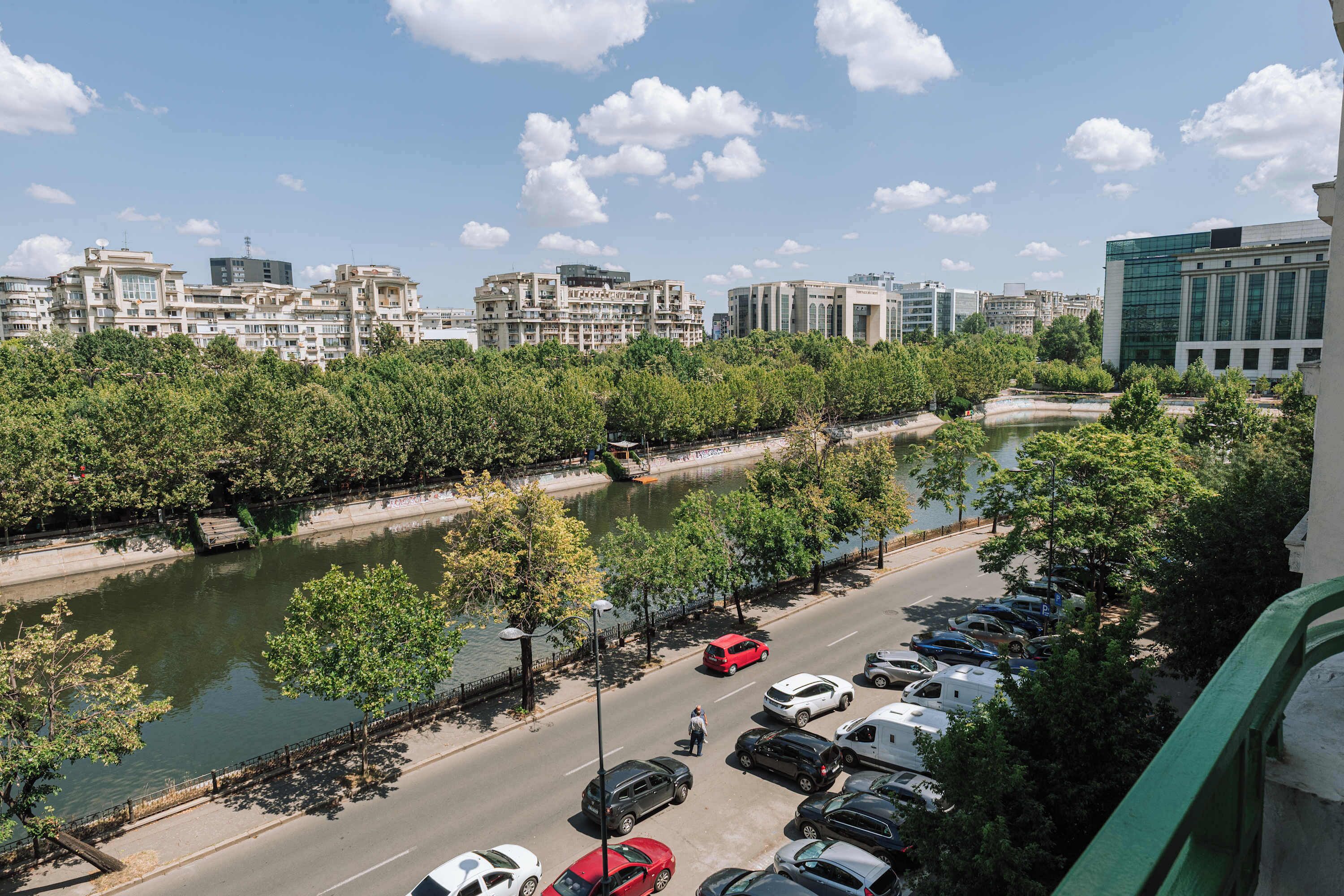 A river with a bridge, a parking lot, and buildings in the background.