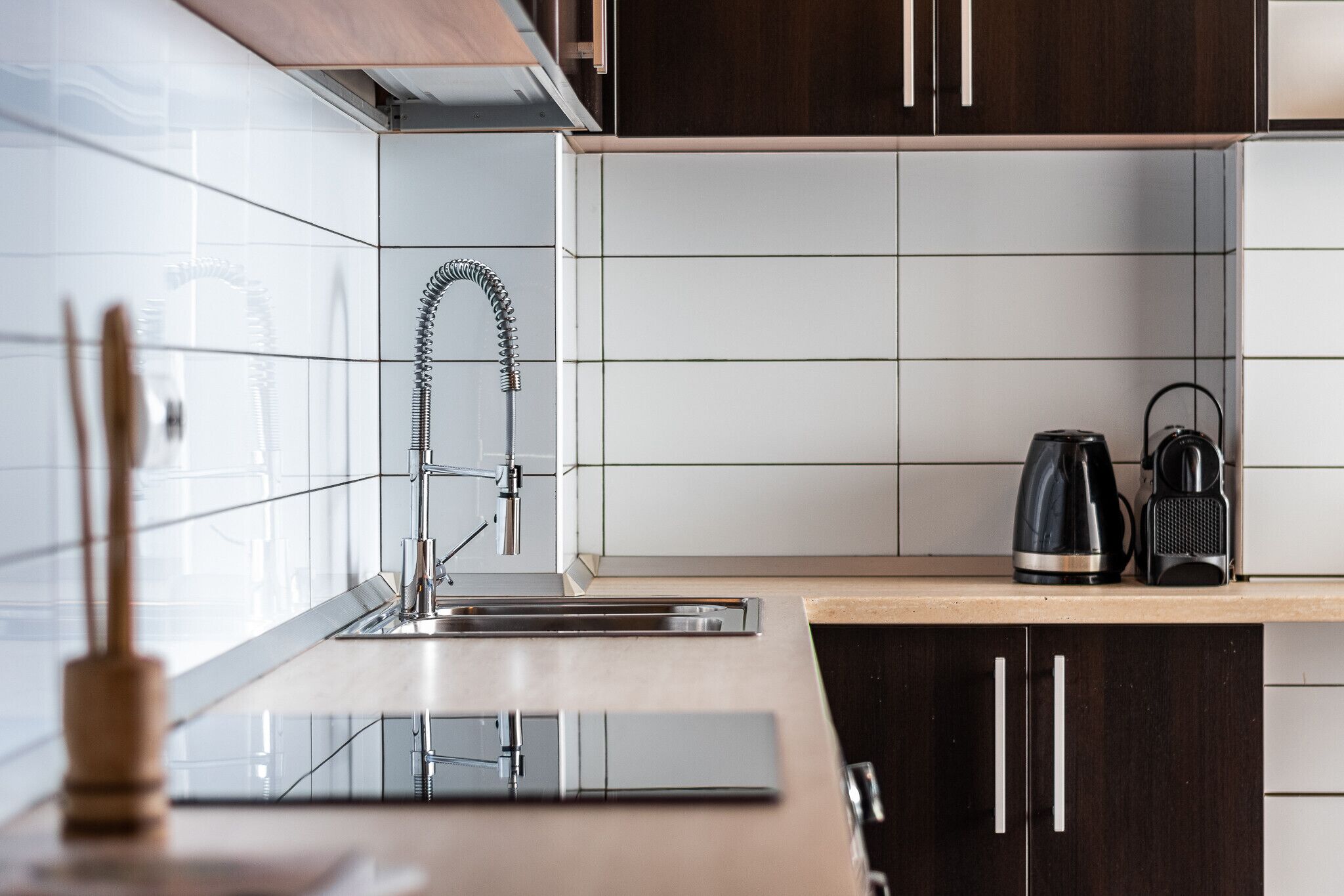 A modern kitchen with a stainless steel sink, a kettle, and a coffee maker on the countertop.