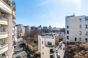 Un edificio urbano de varios pisos con balcones, estacionamiento y cielo despejado.