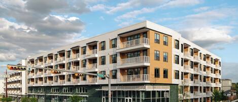 A multi-story hotel with balconies, large windows, and a green facade.