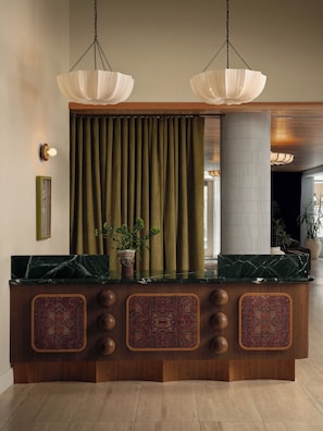 A reception desk with a marble top, wooden base, and decorative panels. - Private Balcony, Resort-Style Amenities, Pool, Dining, Terrace, Views | The Code (Austin)