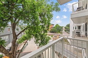 A balcony with a view of a tree, a building, and a street. - Private Balcony, Resort-Style Amenities, Pool, Dining, Terrace, Views | The Code (Austin)